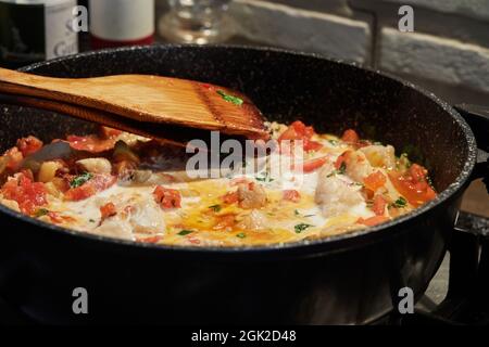 Le poisson-bar avec tomates fenouil et basilic est frit dans une casserole sur le poêle à gaz. Banque D'Images