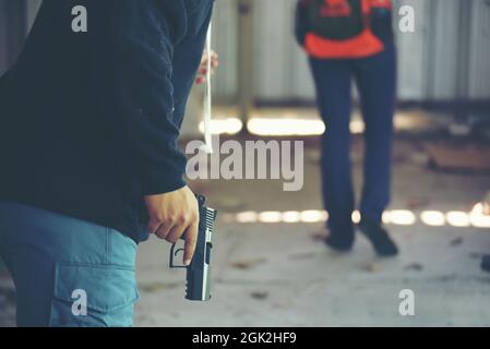 Vol Robber tenir le pistolet à la main essayer de voler le sac à dos du voyageur. Crime de violence criminelle de rue. Banque D'Images