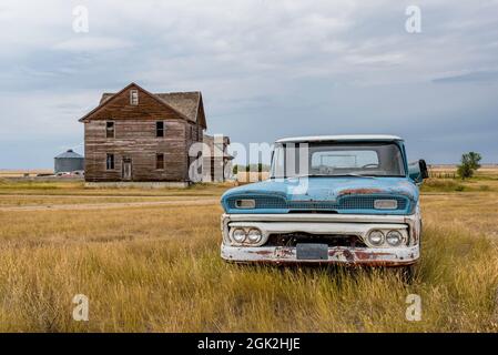 Un pick-up classique bleu et blanc et une maison abandonnée dans la ville fantôme de Robsart, SK Banque D'Images