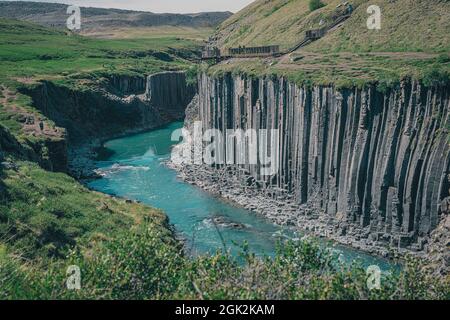 Vue d'ensemble du canyon de Studlagil en Islande, vallée pittoresque avec des colonnes de basalte debout sur une chaude journée d'été. Photo prise dans l'herbe Banque D'Images