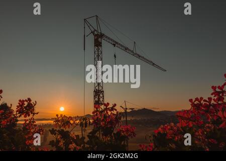 Chantier de construction d'un immeuble d'appartements en début de matinée avec lever du soleil, brume visible et brouillard sur les champs. Photo moderne épique du chantier de construction. Banque D'Images