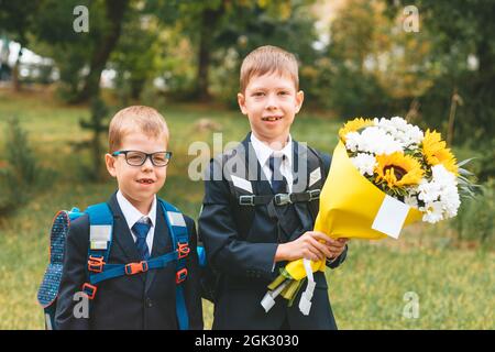 portrait d'un jeune garçon de sept ans, jeunes élèves, portant un bouquet de fleurs avec un petit frère prêt à aller à l'école. concept de retour à l'école. Banque D'Images