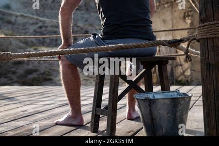 Homme adulte assis sur un banc en bois dans l'anneau de combat Banque D'Images
