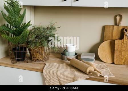 Ustensiles de cuisine dans la cuisine scandinave : arbre de Noël dans une casserole, branches d'épicéa, planches à découper en bois, rouleau et serviette Banque D'Images