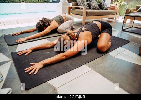 Deux amis se liant à l'exercice à l'extérieur de la maison sur les tapis de gym Banque D'Images
