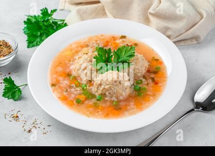 Soupe saine avec boulettes de viande de dinde et légumes dans une assiette blanche sur fond gris. Banque D'Images