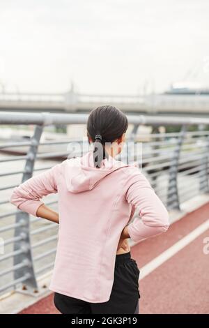 Vue arrière de la jeune femme debout sur le stade de sport et de l'entraînement seul à l'extérieur Banque D'Images