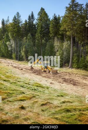 La pelle rétro nivele la surface de la pente pour une pente de ski. Banque D'Images