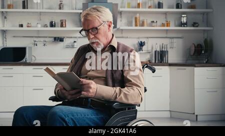 homme âgé handicapé dans un livre de lecture en fauteuil roulant Banque D'Images