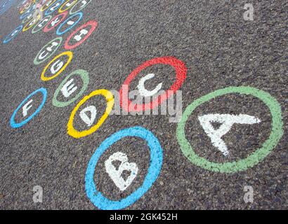 Lettres de l'alphabet en cercles colorés sur une route asphaltée Banque D'Images