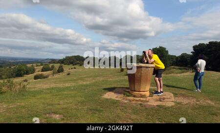 Un marcheur se penche sur le topographe pour prendre une vue éloignée de la colline de Douvres près de Chipping Camden dans Gloucestershire Banque D'Images