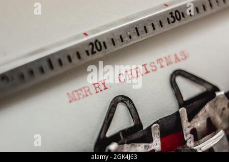 Texte Joyeux Noël imprimé avec des encres rouges sur papier blanc sur machine à écrire rétro. Vue en gros plan Banque D'Images