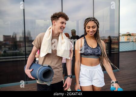 Jeune couple parlant après l'exercice en plein air sur la terrasse, sport et concept de mode de vie sain. Banque D'Images