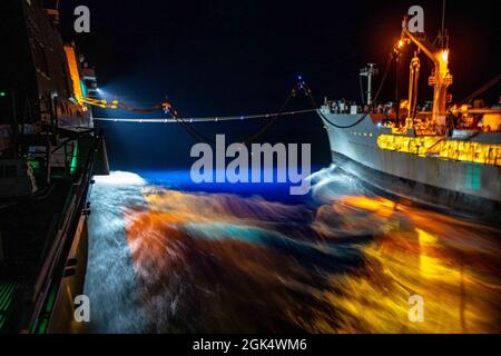 Le quai de transport amphibie de classe San Antonio USS Arlington (LPD 24) navigue à côté de l'auréoleur de la flotte de classe Henry J. Kaiser USNS Joshua Humphreys (T-AO 188) dans l'océan Atlantique le 2 août 2021 pendant une période de nuit en cours de reconstitution. Arlington a pris du carburant à réaction. Banque D'Images