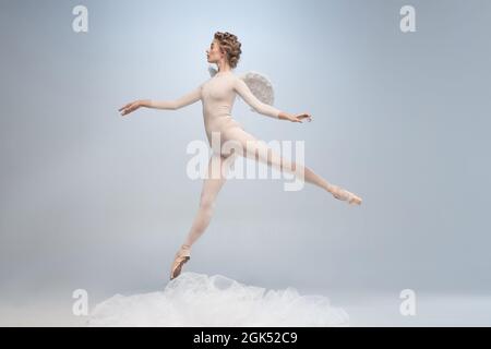 Danseuse de ballet jeune et gracieuse, danseuse de ballerine à l'image d'ange avec des ailes isolées sur fond gris de studio. Art, mouvement, action, flexibilité Banque D'Images