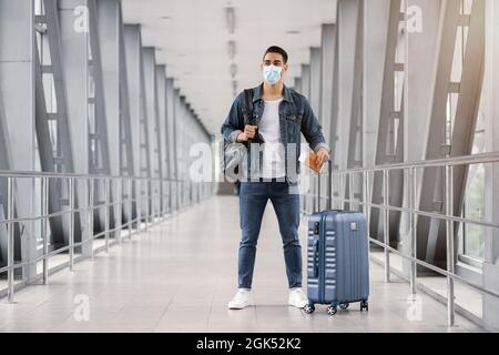 Le coronavirus se déplace. Jeune homme du Moyen-Orient en masque médical debout dans le terminal de l'aéroport Banque D'Images