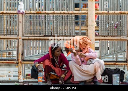 Orcha, Madhya Pradesh, Inde - Mars 2019 : deux pèlerins indiens assis à l'extérieur d'une clôture et ayant une conversation. Banque D'Images