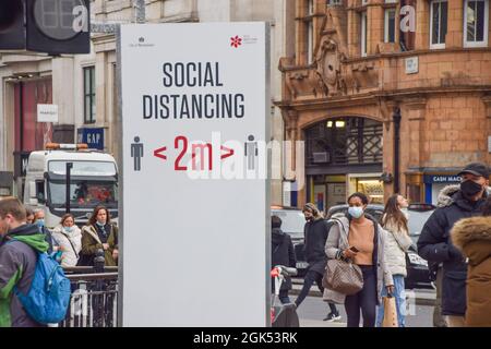 Les personnes portant un masque facial protecteur marchent devant un signe de distance sociale sur Oxford Circus pendant la pandémie du coronavirus. Londres, Royaume-Uni 2 décembre 2020. Banque D'Images