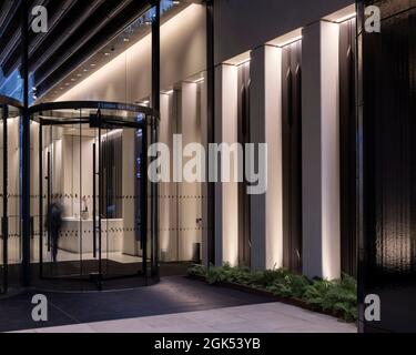 Entrée du bâtiment 2 avec porte tournante et éclairage de colonne. London Wall place, Londres, Royaume-Uni. Architecte : Make Ltd, 2019. Banque D'Images