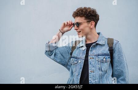 Joyeux jeune homme touriste à l'extérieur sur fond blanc lors d'un voyage en ville, en regardant de côté. Banque D'Images