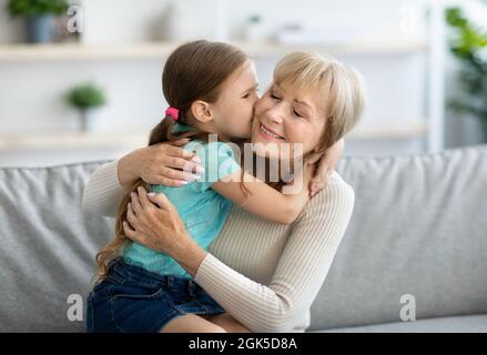 Bonne petite-fille embrassant la granny dans la joue à la maison Banque D'Images