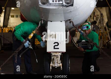 OCÉAN PACIFIQUE (août 6, 2021) Airman Shannon, mécanicien de structures aéronautiques, fuit (à droite), de Tampa, Floride, Et le mécanicien de structures aéronautiques Airman Jordan Bohorquz, de Montebello, en Californie, graisser un train d'atterrissage à nez sur un Hawkeye E-2D, affecté aux “Wallbangers” de l'escadron d'alerte précoce aéroporté (VAW) 117, dans la baie hangar à bord de l'USS Abraham Lincoln (CVN 72). Abraham Lincoln mène actuellement des opérations de routine dans la zone d'exploitation de la 3e flotte américaine. Banque D'Images