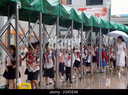 Shanghai, Shanghai en Chine. 13 septembre 2021. Les élèves s'alignent sous l'abri d'un auvent amovible après la classe dans une école primaire dans le district de Huangpu, dans l'est de la Chine Shanghai, le 13 septembre 2021. Shanghai a ordonné aux écoles maternelles, primaires et secondaires de suspendre les cours du lundi après-midi au mardi, alors que la ville s'éveille pour les fortes pluies et les vents forts dus au typhon Chanthu. Credit: Liu Ying/Xinhua/Alay Live News Banque D'Images
