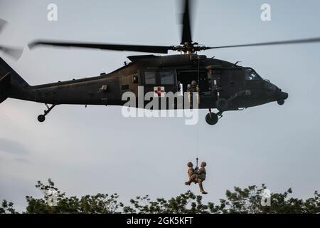 Le 9 août 2021, un paramédic de l'armée américaine avec le chef du diamant de la Force opérationnelle, le 25e Aviation Regiment, et un medic de combat de l'armée américaine avec le Warrior de la Force opérationnelle, sont hissés sur un penetrator de la jungle, un outil utilisé pour extraire les victimes ambulatoires des zones fortement boisées, dans la zone d'entraînement de Baturaja, en Indonésie. Garuda Shield 21 est un exercice conjoint de deux semaines entre l'armée américaine et les forces armées indonésiennes de Tentara (TNI-AD Indonesia Army Forces). Le but de cet exercice conjoint est d'améliorer et d'enrichir la capacité de guerre dans la jungle de l'armée américaine et de l'armée indonésienne. Banque D'Images