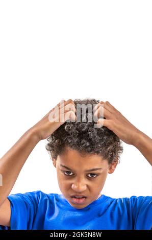 Jeune garçon souriant se grattant les cheveux pour les poux ou les allergies. Banque D'Images