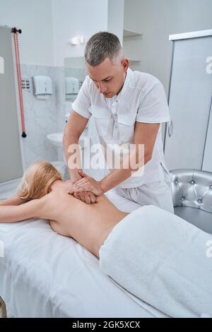 Ostéopathe concentré expérimenté utilisant une technique chiropratique Banque D'Images