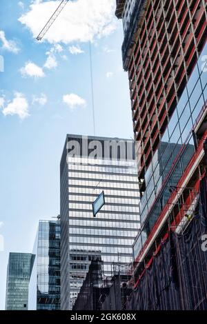 Grue de construction guidant un panneau de verre géant pour l'installation dans un gratte-ciel sur Fifth Avenue, New York City, USA 2021 Banque D'Images