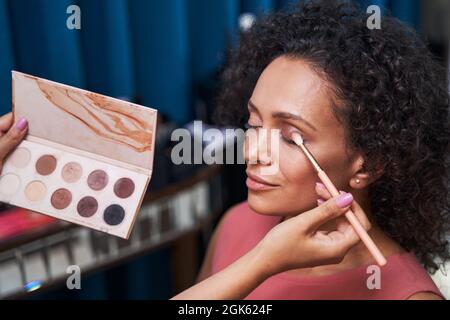 Photo focalisée sur la brunette femme faisant du maquillage Banque D'Images