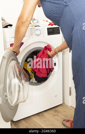 Vue arrière d'une femme mettant des vêtements dans un lave-linge Banque D'Images