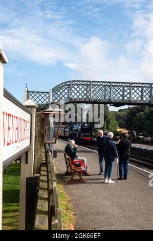 Train à vapeur arrivant à la plate-forme de la station Weyborne avec des personnes attendant d'embarquer un jour d'été à norfolk Banque D'Images