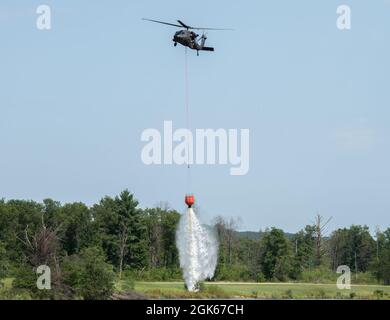 Une équipe de la Garde nationale de l'armée du Wisconsin UH-60 Black Hawk avec le 1er Bataillon de Madison, Wisconsin, 147e Aviation Regiment train pour faire tomber de l'eau sur les feux de forêt le 12 août 2021, en utilisant des seaux Bambi dans un lac à fort McCoy, Wisconsin, en préparation du déploiement en Californie. Deux avions et 17 soldats de l'unité ont quitté le Wisconsin le 13 août 2021 pour combattre les feux de forêt en Californie. Banque D'Images