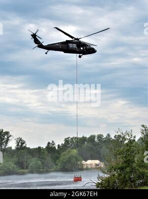 Une équipe de la Garde nationale de l'armée du Wisconsin UH-60 Black Hawk avec le 1er Bataillon de Madison, Wisconsin, 147e Aviation Regiment train pour faire tomber de l'eau sur les feux de forêt le 12 août 2021, en utilisant des seaux Bambi dans un lac à fort McCoy, Wisconsin, en préparation du déploiement en Californie. Deux avions et 17 soldats de l'unité ont quitté le Wisconsin le 13 août 2021 pour combattre les feux de forêt en Californie. Banque D'Images