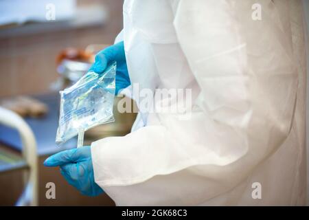 Les mains du médecin dans des gants en caoutchouc tiennent la solution compte-gouttes. Banque D'Images