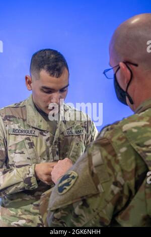 SPC. Antonio Rodriguez, spécialiste des communications de masse dans les affaires publiques, avec le 206e détachement des opérations de radiodiffusion, le 205e élément de soutien aux affaires publiques du théâtre, la 63e Division de la préparation – Groupe de soutien du commandement de la mission, à gauche, et le Sgt. Clinton Massey, spécialiste des communications de masse dans les affaires publiques du 206e Détachement des opérations de radiodiffusion, à droite, prépare un micro-cravate en vue d'une émission télévisée enregistrée dans le cadre de l'opération News Day le 17 août 2021, à fort McCoy, dans le Wisconsin. La 206e BOD a mené sa formation annuelle à fort McCoy. Banque D'Images