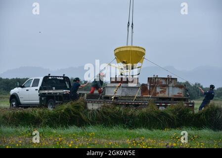 La Garde côtière américaine aide à la navigation l'équipe Astoria verse du béton dans une base d'aide à la navigation à partir d'un conteneur soulevé par un hélicoptère Columbia River MH-60 Jayhawk du secteur de la Garde côtière, le mercredi 18 août 2021, à Astoria, Oregon. Les deux équipes ont mené la formation sur le béton pour se préparer à un projet de reconstruction à venir, où elles pourront servir de base pour de nouvelles aides à la navigation. Banque D'Images