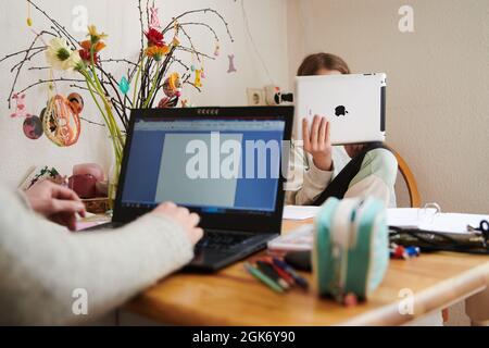 Berlin, Allemagne. 29 avril 2021. Une mère travaille à la table de cuisine tandis que sa fille regarde dans une tablette en face d'elle. Credit: Annette Riedl/dpa/Alay Live News Banque D'Images
