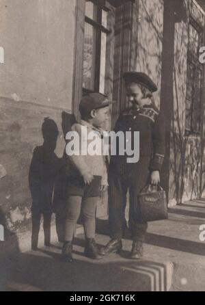 Un petit garçon va à la crèche avec sa grande sœur qui va à l'école après qu'elle a laissé tomber son frère dans la crèche des années 1940 Banque D'Images