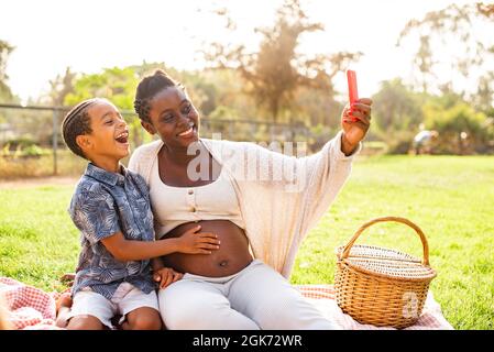Femme noire enceinte et garçon prenant le selfie ensemble Banque D'Images