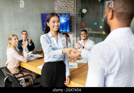 Black Boss se serrer la main et féliciter les femmes asiatiques pour leur réussite commerciale Banque D'Images