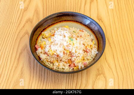 Riz aux légumes, au jambon, à la ciboulette, aux carottes et aux omelettes sautées au restaurant chinois dans un bol sombre Banque D'Images