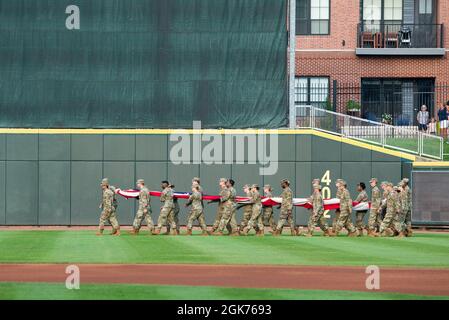 Des aviateurs de la base aérienne Wright-Patterson lancent un grand drapeau sur le terrain lors de l'événement des héros de la ville natale de Dayton Dragons au Day Air Credit Union Ballpark, le 21 août 2021, à Dayton, Ohio. En plus de réaliser le drapeau, les militaires ont également lancé le premier terrain, chanté l'hymne national et présenté les couleurs lors des cérémonies de prépartie. Banque D'Images