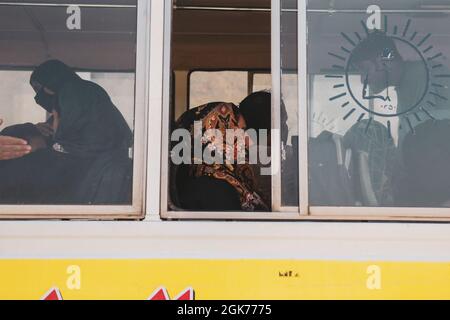 210822-M-TU241-1014 AÉROPORT INTERNATIONAL HAMID KARZAÏ (Afghanistan) (22 août 2021) Une femme attend un autobus pour être traitée lors d'une évacuation à l'aéroport international Hamid Karzaï, Kaboul (Afghanistan), le 22 août. Les membres du service américain aident le ministère d'État à effectuer une opération d'évacuation non combattantes (NEO) en Afghanistan. Banque D'Images