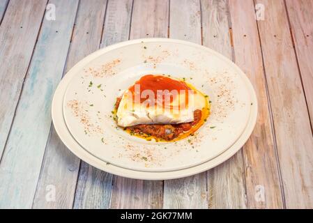 Assiette de taco de morue grillé sur un lit de pisto de Manchego et avec crème de tomate sur le dessus Banque D'Images