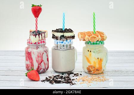 trio de smoothies avec gâteau au cheesecake et fraises, smoothie au chocolat et tart au chocolat et smoothie aux fruits de la passion avec gaufres Banque D'Images