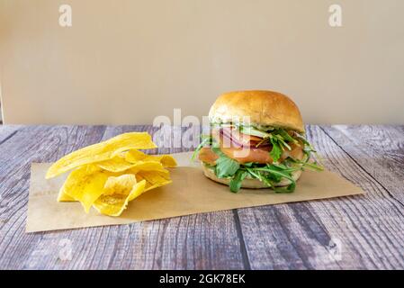 Sandwich au pain de brioche farci de saumon fumé norvégien, avocat mûr et arugula garni de chips de banane frites Banque D'Images