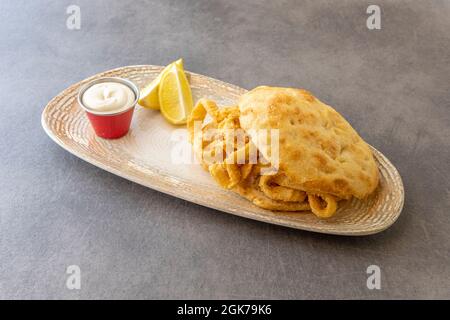 Muffin aux rondelles de calmar battues dans l'œuf et la farine et frites dans l'huile d'olive avec de la mayonnaise et des quartiers de citron Banque D'Images